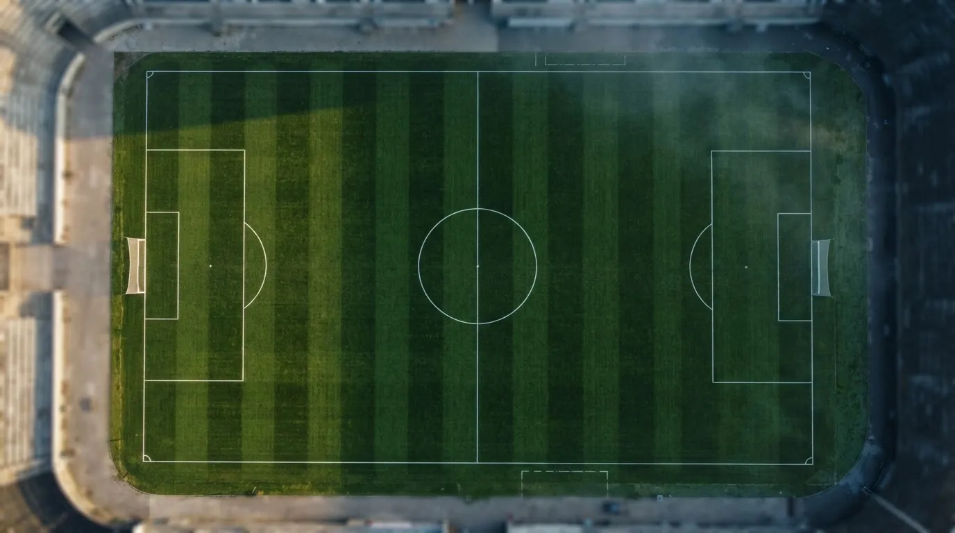 Ein Fussballplatz von oben gesehen, die Linien bilden ein helles Muster auf dem Rasen, Drohnenperspektive in der Morgendämmerung.